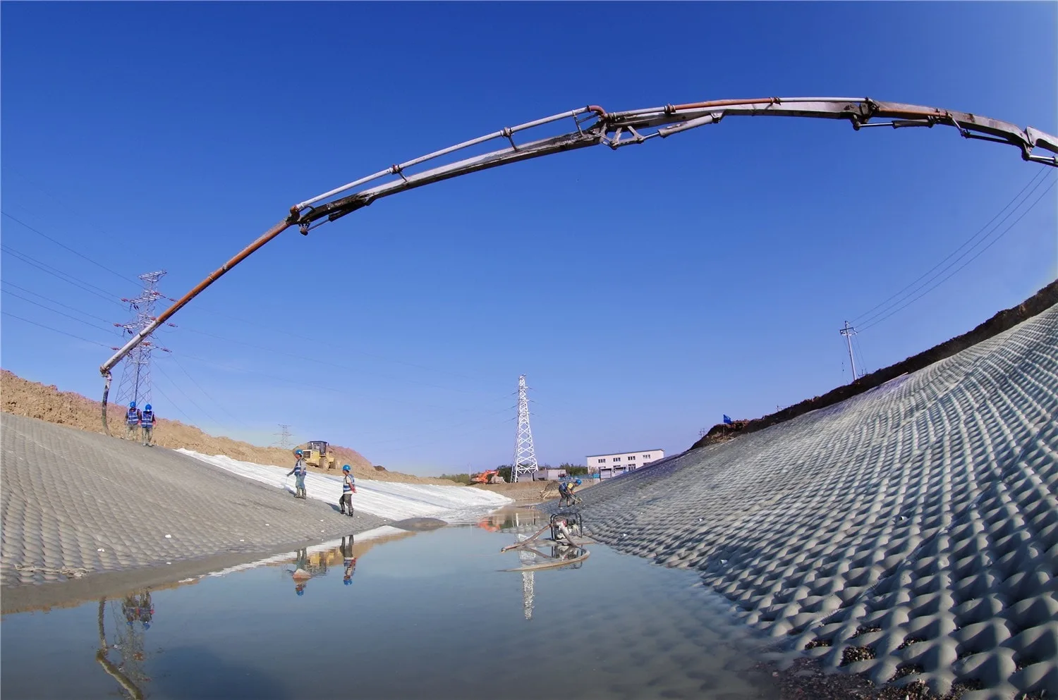 Pump boom extending over canal during grouted mattress installation