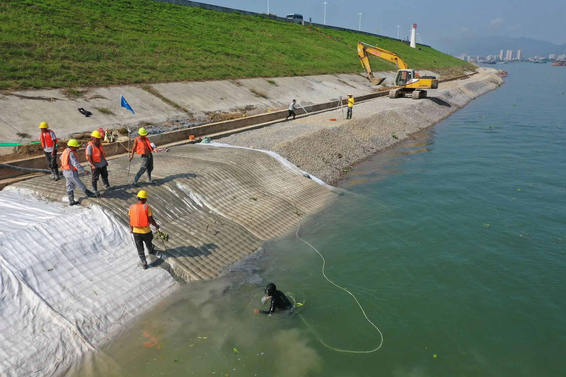 Diver and surface crew installing underwater toe protection for coastal revetment