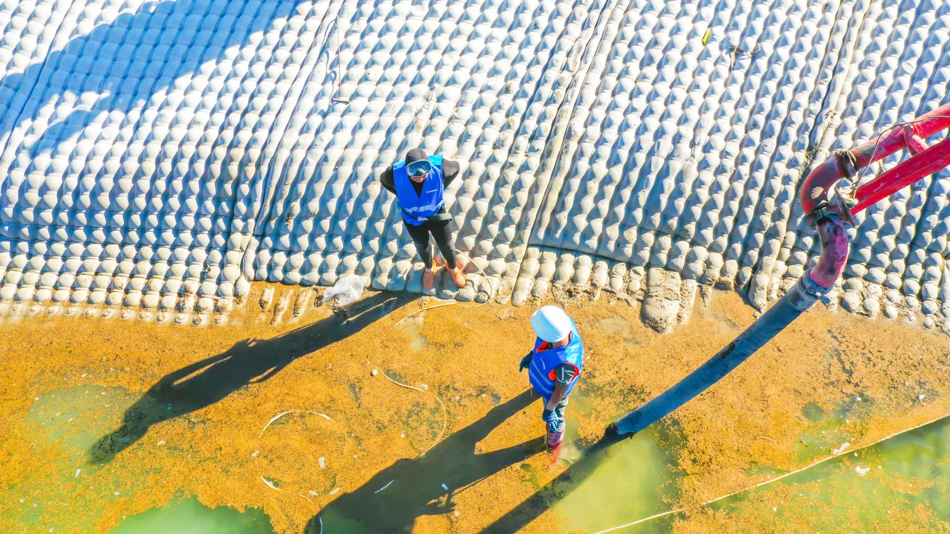 Overhead drone shot of workers on installed grouted mattress surface