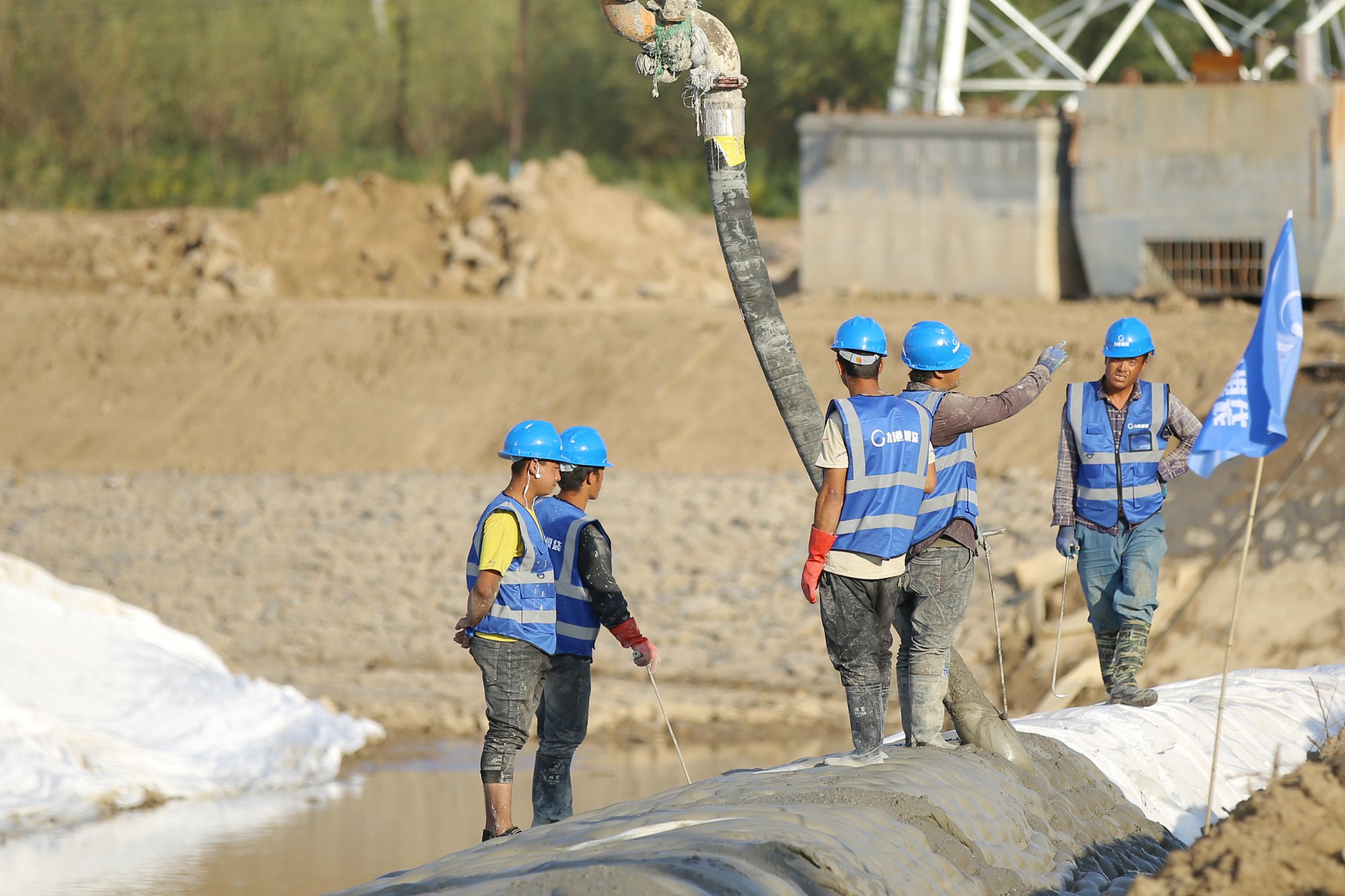 Crew grouting mattress on river bank with pump hose