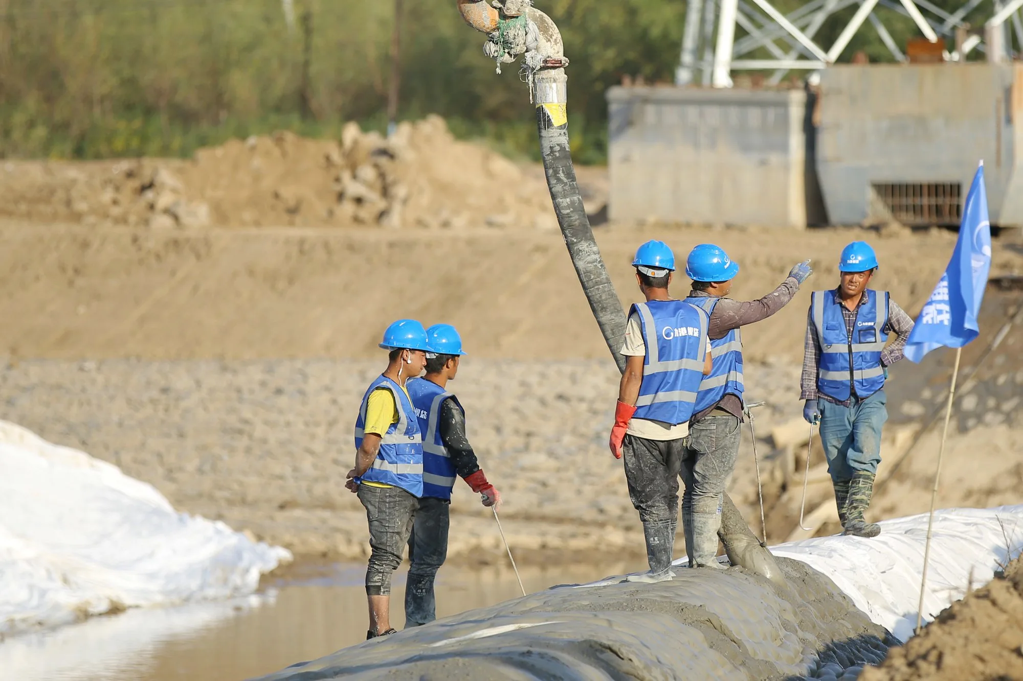 Crew grouting mattress on river bank with pump hose