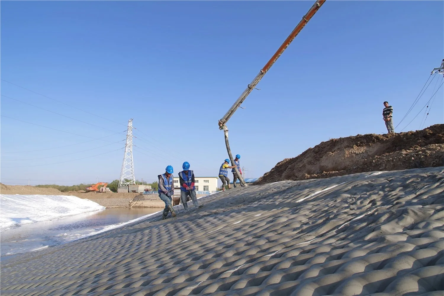 Installation crew pumping cement grout into fabric formed concrete mattress on canal slope