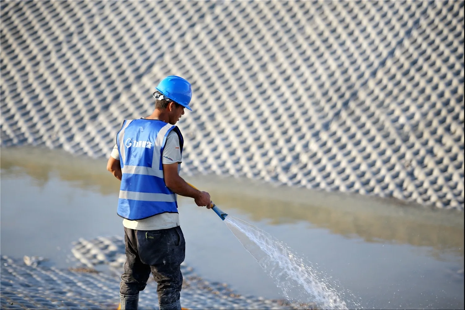 Worker curing grouted mattress with water