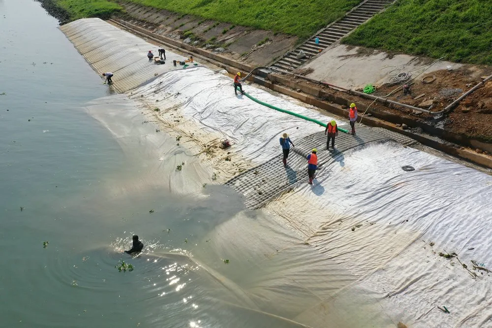 Workers grouting mattress at coastal pier base